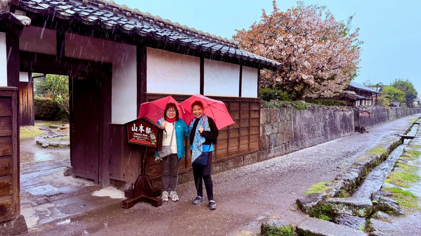 Two women standing outside in rain in rural Japan