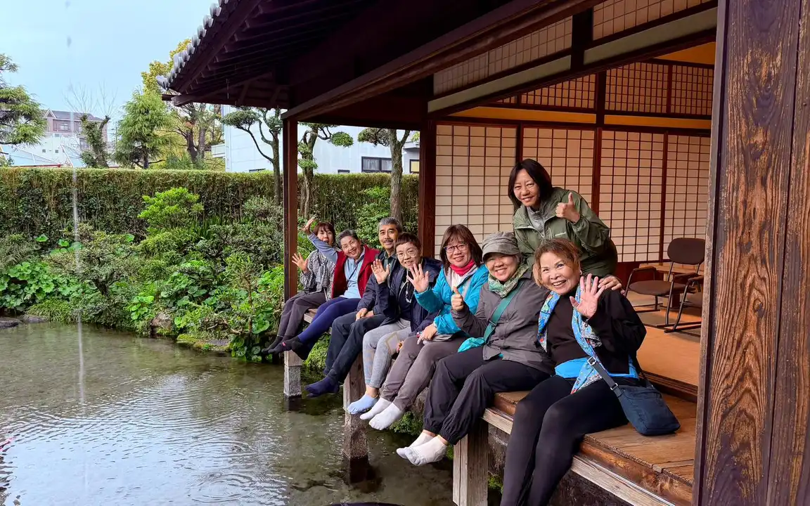 From the Autumn Tour in 2024, a group of tourists stop for a photo beneath Aso
