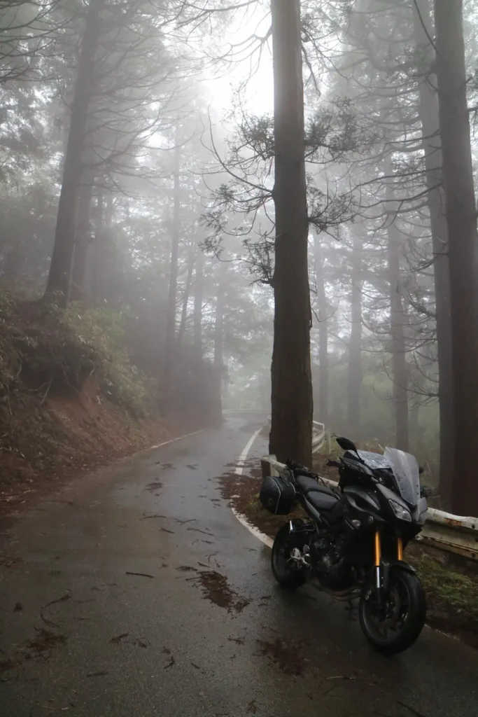 A motorcycle parked on the road side in rural Kyushu in a foggy forest
